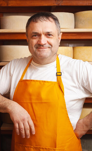 Portrait d'un artisan fromager devant ses fromages