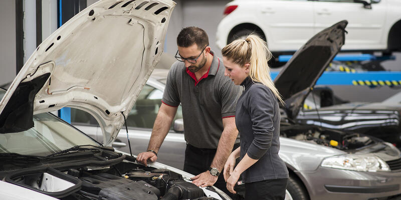 Une apprentie avec son maitre d'apprentissage étudiant le moteur d'une voiture