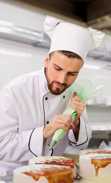 Pâtissier faisant le glaçage de ses gâteaux