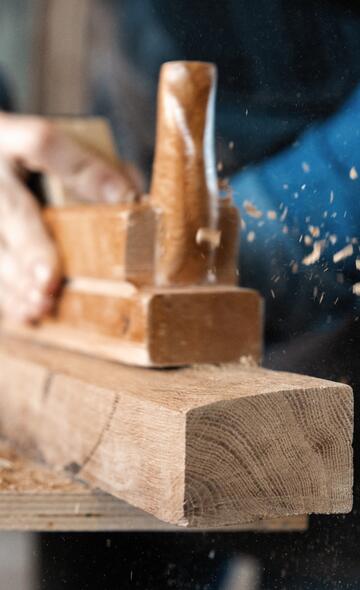 Artisan menuisier rabotant une planche de bois