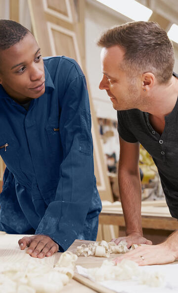 Un artisan charpentier discute avec son nouvel employé