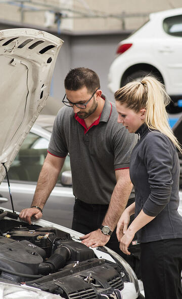 Une apprentie avec son maitre d'apprentissage étudiant le moteur d'une voiture