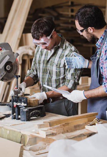 Jeune apprentis menuisier avec son maitre d'apprentissage