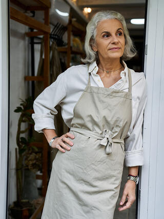 Artisane appuyée sur la porte de l'entreprise qu'elle souhaite transmettre