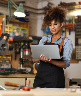 Jeune femme sur son ordinateur au sein de l'atelier de l'entreprise qu'elle a créée