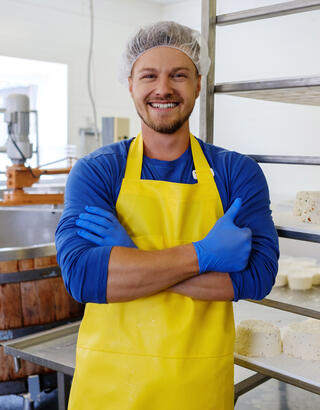 Artisan fromager devant ses cuves et ses fromages