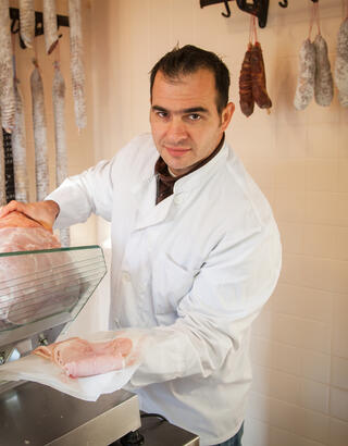 Artisan charcutier découpant des tranches de jambon