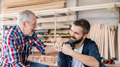 Un artisan souriant complice avec l'artisan à qui il transmet son entreprise 
